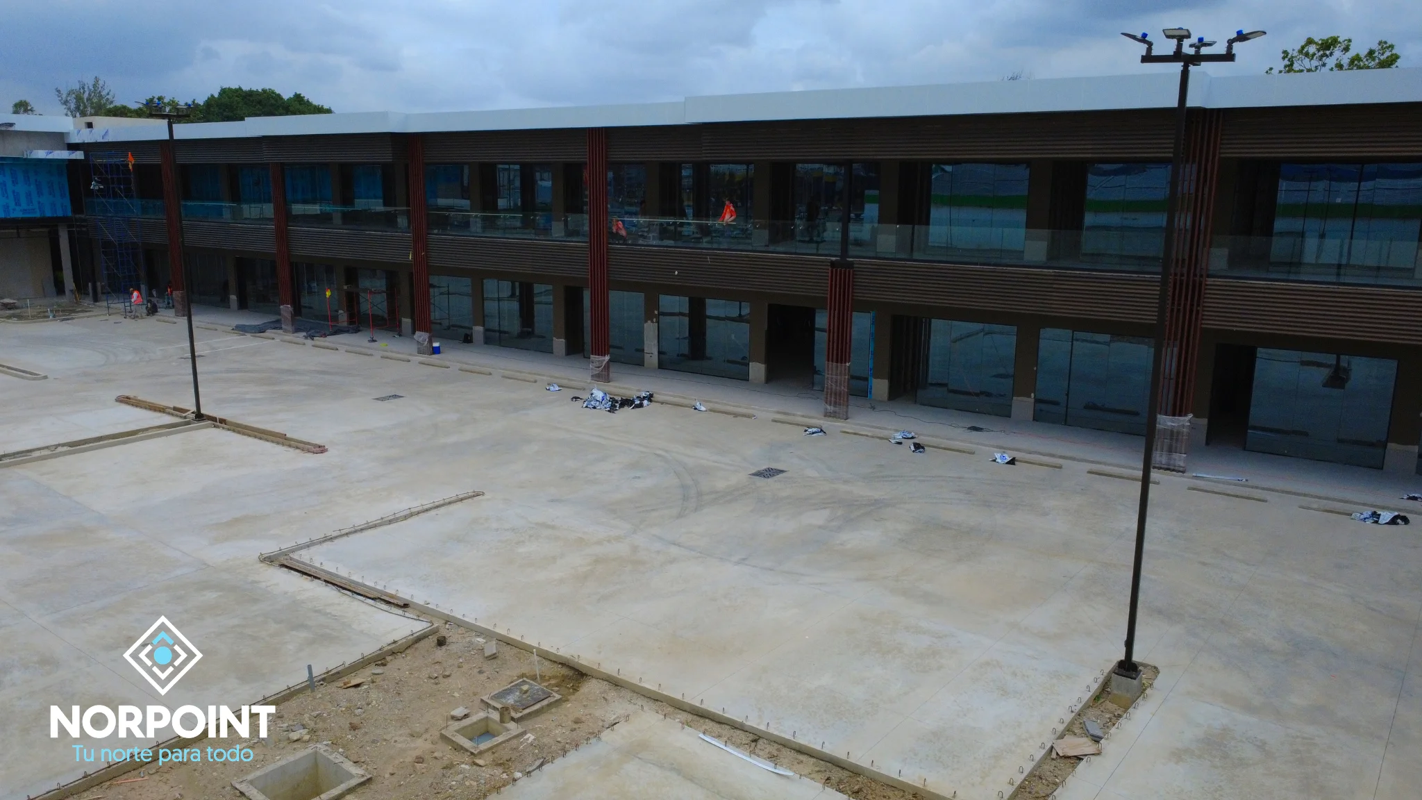 Avance de julio en Norpoint con pasillo exterior en desarrollo, locales comerciales alineados y trabajos de piso en proceso.